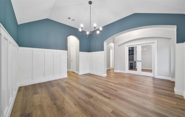 28006 Brendon Trail Ct, Spring, TX 77386 - empty room with lofted ceiling, arched walkways, wood finished floors, french doors, and a chandelier