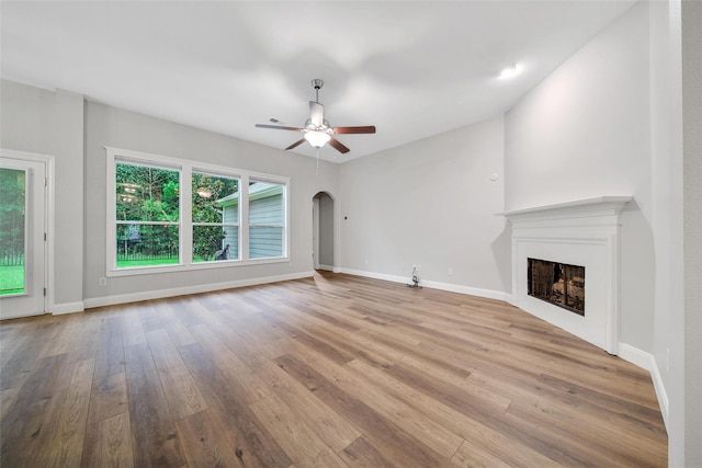 28006 Brendon Trail Ct, Spring, TX 77386 - unfurnished living room with arched walkways, wood finished floors, ceiling fan, and a fireplace