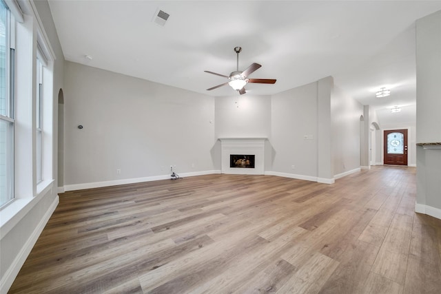 28006 Brendon Trail Ct, Spring, TX 77386 - unfurnished living room featuring arched walkways, ceiling fan, a fireplace, and light wood-type flooring