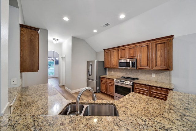 28006 Brendon Trail Ct, Spring, TX 77386 - kitchen with stainless steel appliances, light stone countertops, tasteful backsplash, lofted ceiling, and brown cabinets