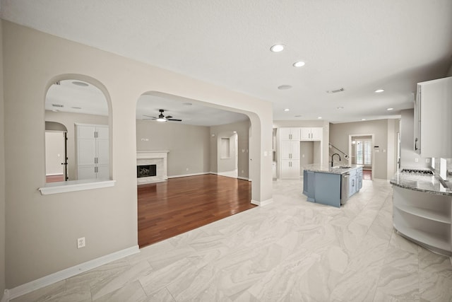 22419 Rippling Shore Ct, Katy, TX 77494 - unfurnished living room with a ceiling fan, recessed lighting, a high end fireplace, light marble finish flooring, and arched walkways