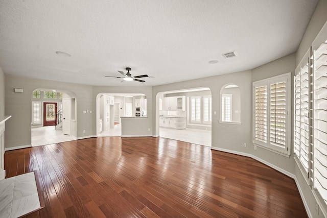 22419 Rippling Shore Ct, Katy, TX 77494 - unfurnished living room with arched walkways, ceiling fan, hardwood / wood-style floors, and a textured ceiling