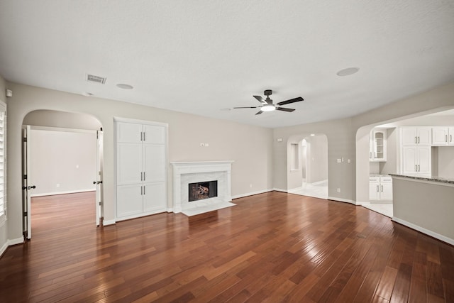 22419 Rippling Shore Ct, Katy, TX 77494 - unfurnished living room featuring arched walkways, ceiling fan, dark wood-style flooring, and a fireplace