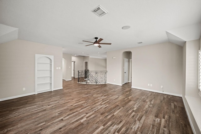 22419 Rippling Shore Ct, Katy, TX 77494 - unfurnished living room featuring arched walkways, dark wood-style flooring, a ceiling fan, and built in shelves