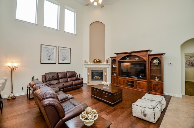 24914 Hazel Ranch Dr, Katy, TX 77494 - living room with arched walkways, a high ceiling, a ceiling fan, a fireplace, and wood finished floors