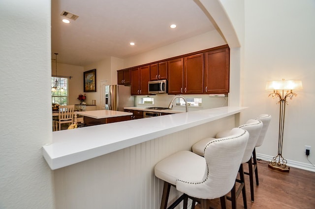 24914 Hazel Ranch Dr, Katy, TX 77494 - kitchen with stainless steel appliances, a peninsula, dark wood finished floors, light countertops, and arched walkways