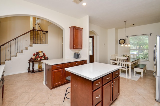 24914 Hazel Ranch Dr, Katy, TX 77494 - kitchen with light tile patterned flooring, a center island, a chandelier, hanging light fixtures, and freestanding refrigerator