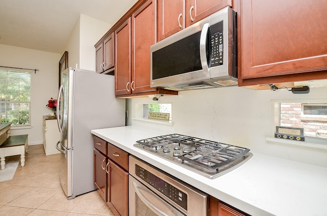 24914 Hazel Ranch Dr, Katy, TX 77494 - kitchen with appliances with stainless steel finishes, light countertops, light tile patterned floors, and brown cabinetry