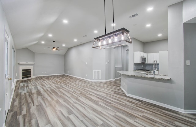 22718 Red Pine Dr, Tomball, TX 77375 - unfurnished living room with a ceiling fan, light wood-type flooring, lofted ceiling, recessed lighting, and a glass covered fireplace