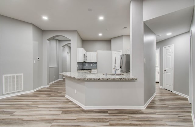 22718 Red Pine Dr, Tomball, TX 77375 - kitchen with appliances with stainless steel finishes, light wood-style floors, white cabinets, light stone countertops, and decorative backsplash