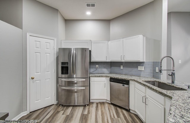 22718 Red Pine Dr, Tomball, TX 77375 - kitchen featuring stainless steel appliances, light wood finished floors, decorative backsplash, and white cabinets