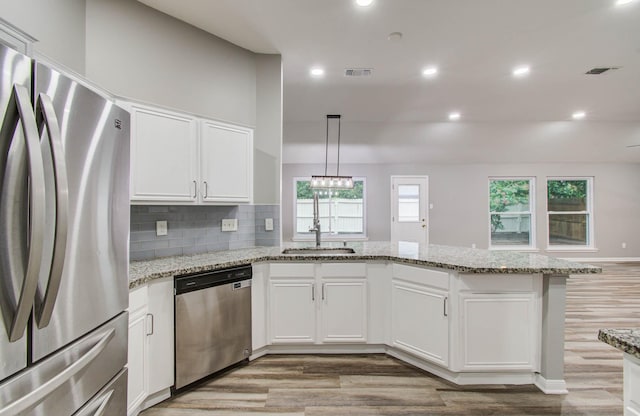 22718 Red Pine Dr, Tomball, TX 77375 - kitchen featuring appliances with stainless steel finishes, a peninsula, light wood-type flooring, white cabinetry, and light stone counters
