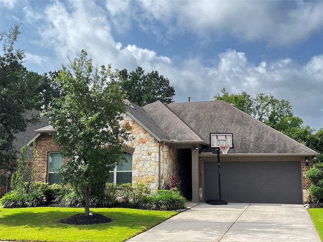 9327 Victory Canyon Ln, Tomball, TX 77375 - view of front facade featuring stone siding, an attached garage, a front lawn, concrete driveway, and roof with shingles