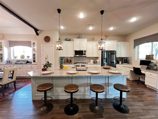 9327 Victory Canyon Ln, Tomball, TX 77375 - kitchen featuring stainless steel microwave, black fridge with ice dispenser, tasteful backsplash, white cabinetry, and recessed lighting