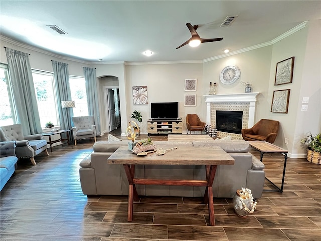 9327 Victory Canyon Ln, Tomball, TX 77375 - living area featuring ornamental molding, a tile fireplace, ceiling fan, wood finish floors, and arched walkways