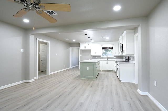 1302 W Adoue St, Alvin, TX 77511 - kitchen with stainless steel appliances, ceiling fan, light wood-type flooring, a kitchen island, and white cabinets