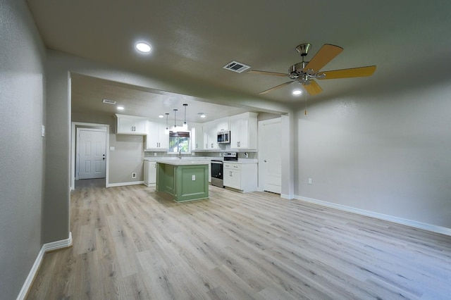 1302 W Adoue St, Alvin, TX 77511 - kitchen featuring stainless steel appliances, light wood-style flooring, white cabinets, a ceiling fan, and a kitchen island
