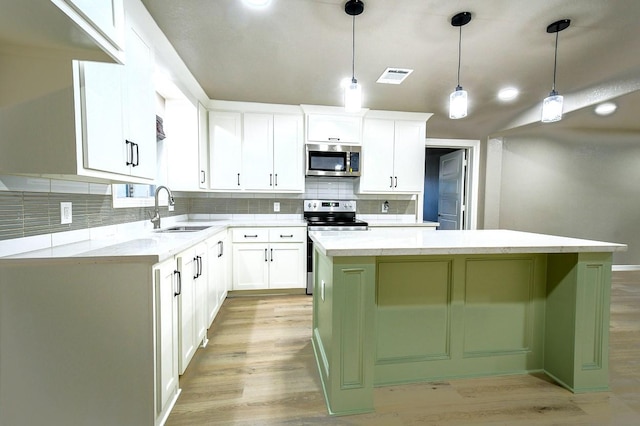 1302 W Adoue St, Alvin, TX 77511 - kitchen featuring stainless steel appliances, light wood finished floors, a kitchen island, and backsplash