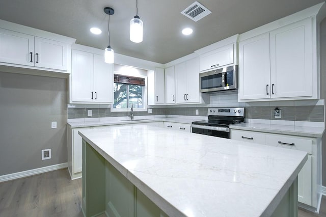 1302 W Adoue St, Alvin, TX 77511 - kitchen with stainless steel appliances, light wood-style floors, tasteful backsplash, white cabinets, and recessed lighting