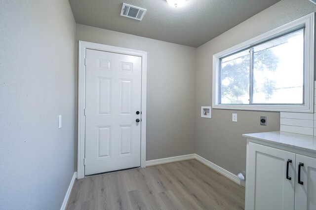 1302 W Adoue St, Alvin, TX 77511 - washroom with hookup for an electric dryer, light wood-style flooring, washer hookup, cabinet space, and a textured ceiling