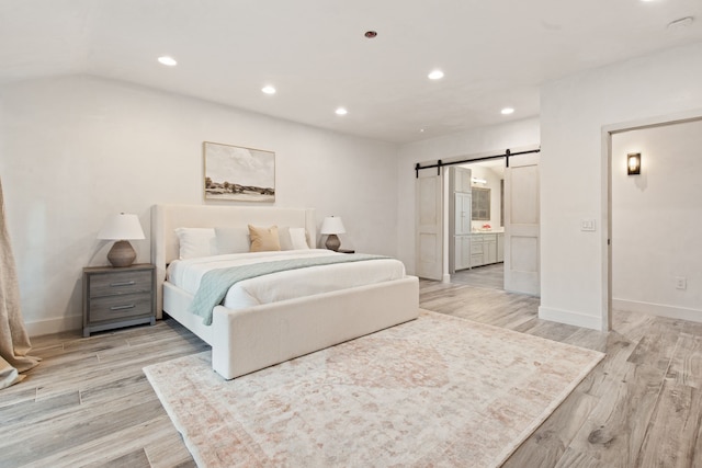 7202 Hartland Ave, Houston, TX 77055 - bedroom with a barn door, light wood-style floors, recessed lighting, and ensuite bathroom