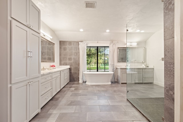 7202 Hartland Ave, Houston, TX 77055 - bathroom with two vanities, a freestanding bath, tile patterned flooring, and recessed lighting