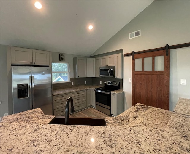 126 2nd Ave, Onalaska, TX 77360 - kitchen with stainless steel appliances, light stone countertops, a barn door, gray cabinets, and recessed lighting
