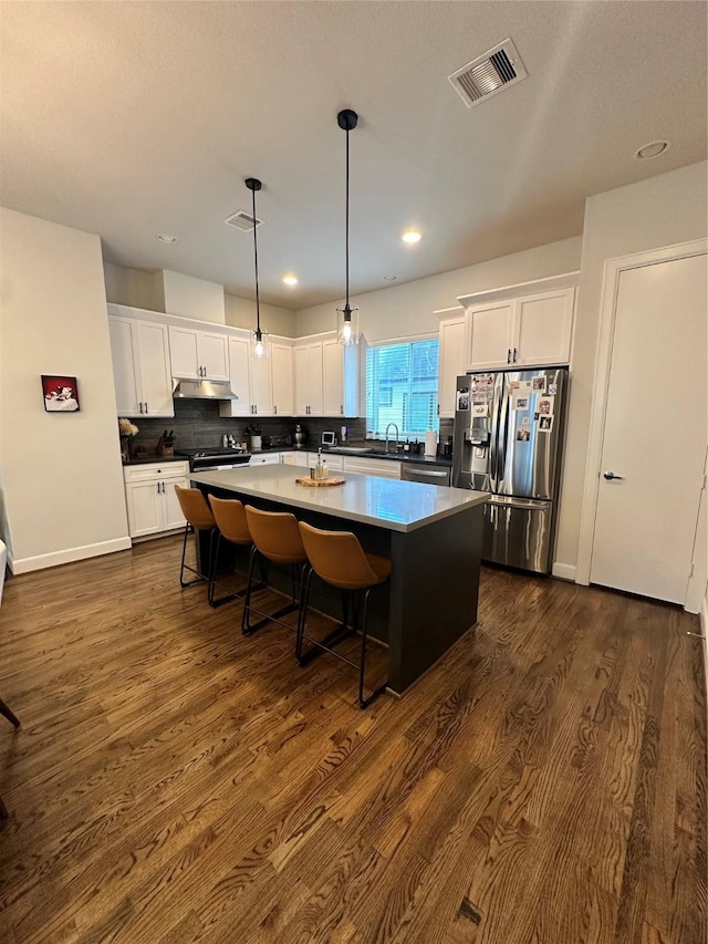 311 Eado Park Cir, Houston, TX 77020 - kitchen featuring stainless steel refrigerator with ice dispenser, a kitchen island, white cabinets, dark wood-style floors, and under cabinet range hood