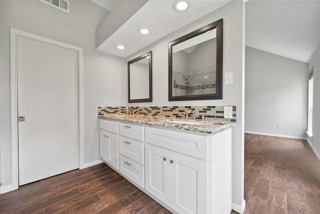 3518 Grove Oaks Dr, Houston, TX 77339 - full bathroom featuring double vanity, tiled shower, wood finished floors, backsplash, and vaulted ceiling