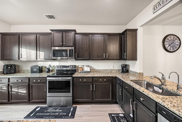 11034 Hillside Creek Dr, Humble, TX 77396 - kitchen featuring appliances with stainless steel finishes, light wood-type flooring, and light stone counters