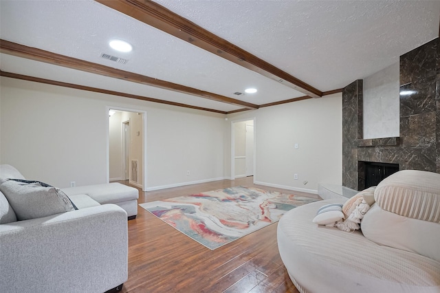 13506 Sherwood St, Sugar Land, TX 77498 - living room with wood finished floors, a textured ceiling, a tiled fireplace, beam ceiling, and recessed lighting