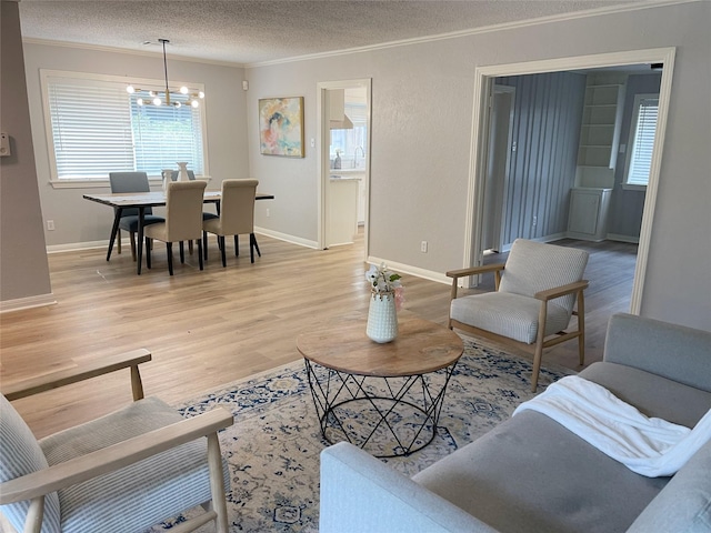 3402 Gannett St, Houston, TX 77025 - living room featuring a textured ceiling, ornamental molding, healthy amount of natural light, light wood finished floors, and a chandelier