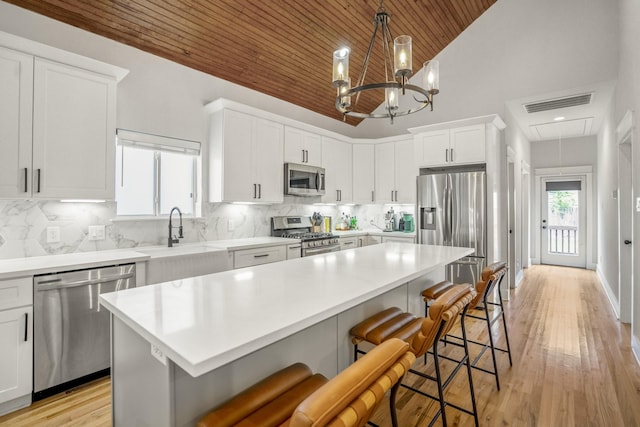 703 Dumble St, Houston, TX 77023 - kitchen featuring stainless steel appliances, wood ceiling, white cabinetry, light countertops, and a breakfast bar