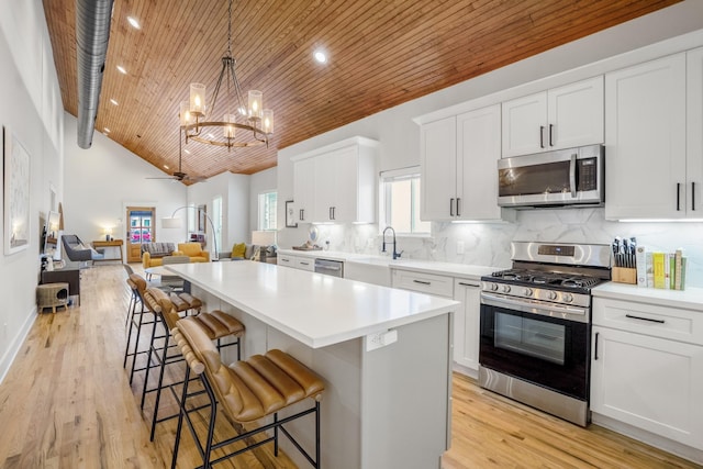 703 Dumble St, Houston, TX 77023 - kitchen with appliances with stainless steel finishes, wooden ceiling, a kitchen island, open floor plan, and a breakfast bar area