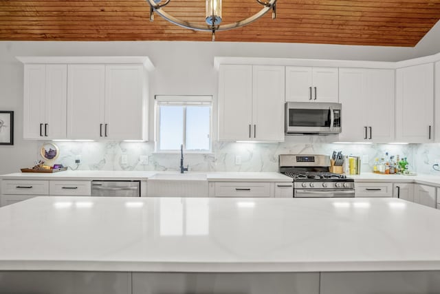 703 Dumble St, Houston, TX 77023 - kitchen featuring stainless steel appliances, wood ceiling, light countertops, white cabinetry, and tasteful backsplash