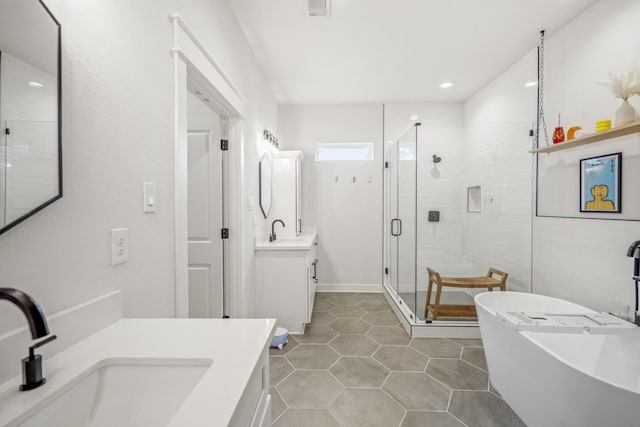 703 Dumble St, Houston, TX 77023 - full bathroom with a stall shower, a freestanding tub, two vanities, tile patterned flooring, and recessed lighting