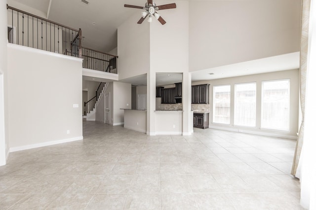 2131 Blossomcrown Dr, Katy, TX 77494 - unfurnished living room featuring a ceiling fan, stairs, a towering ceiling, and light tile patterned floors
