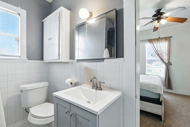 619 10th St, Hempstead, TX 77445 - half bathroom featuring vanity, healthy amount of natural light, ensuite bathroom, a ceiling fan, and tile walls