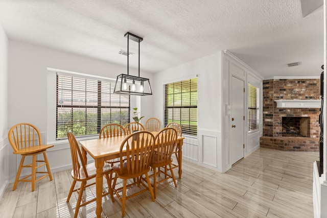 2811 Blue Glen Ln, Houston, TX 77073 - dining space featuring healthy amount of natural light, a decorative wall, a textured ceiling, a fireplace, and light wood-type flooring
