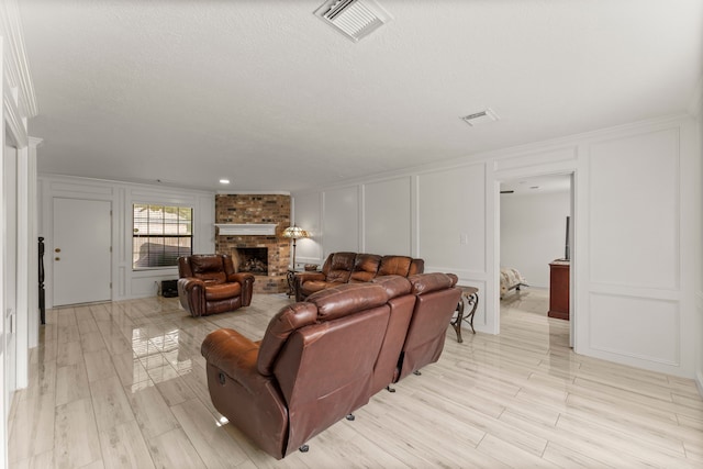 2811 Blue Glen Ln, Houston, TX 77073 - living room featuring a decorative wall, a fireplace, light wood-style floors, crown molding, and a textured ceiling