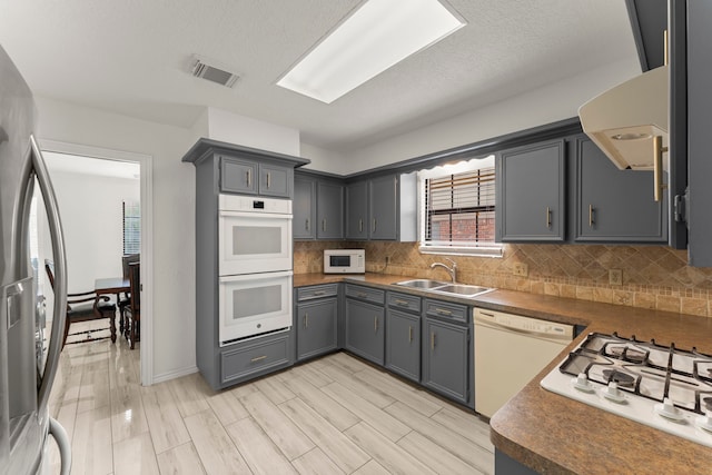 2811 Blue Glen Ln, Houston, TX 77073 - kitchen featuring white appliances, dark countertops, tasteful backsplash, gray cabinetry, and ventilation hood