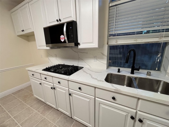 17427 Marigold Dr, Sugar Land, TX 77479 - kitchen featuring stainless steel microwave, black gas cooktop, white cabinets, light stone countertops, and light tile patterned flooring