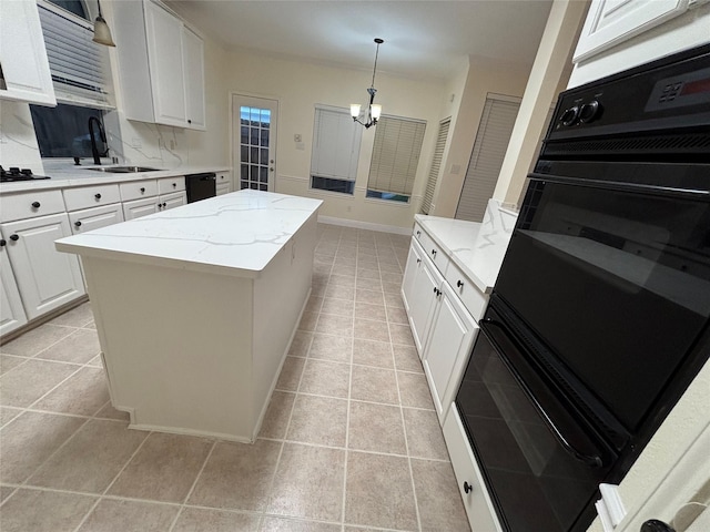 17427 Marigold Dr, Sugar Land, TX 77479 - kitchen featuring black appliances, a kitchen island, light stone countertops, a chandelier, and white cabinetry