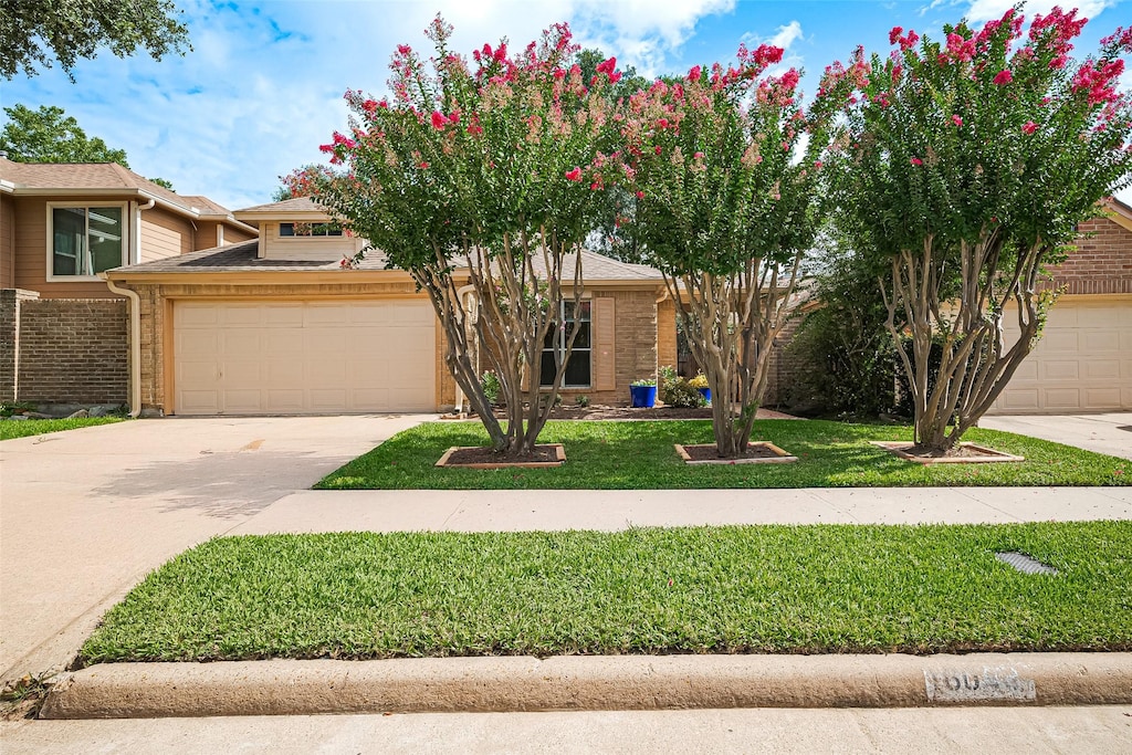 16038 Hidden Acres Dr, Houston, TX 77084 - view of property hidden behind natural elements featuring concrete driveway, brick siding, a front lawn, and an attached garage