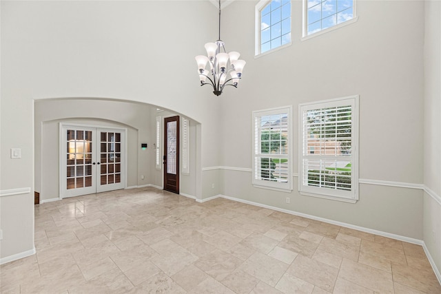 3102 Hillside Landing Trl, Katy, TX 77494 - unfurnished room featuring french doors, a chandelier, arched walkways, a high ceiling, and light stone finish flooring