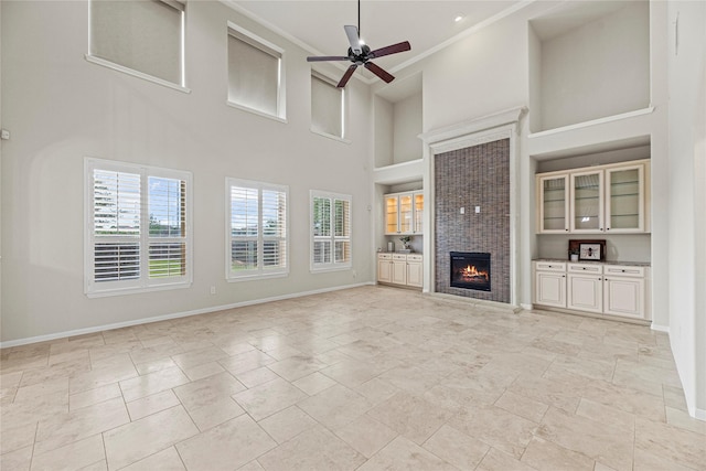 3102 Hillside Landing Trl, Katy, TX 77494 - unfurnished living room with healthy amount of natural light, a high ceiling, ceiling fan, a tiled fireplace, and light stone finish floors
