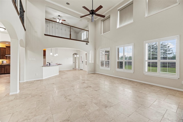 3102 Hillside Landing Trl, Katy, TX 77494 - unfurnished living room featuring ceiling fan, arched walkways, and a towering ceiling