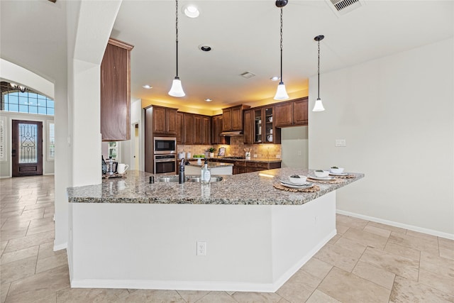 3102 Hillside Landing Trl, Katy, TX 77494 - kitchen featuring stainless steel appliances, light stone countertops, arched walkways, a peninsula, and tasteful backsplash