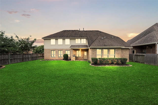 3102 Hillside Landing Trl, Katy, TX 77494 - back of property at dusk featuring brick siding, a fenced backyard, and a shingled roof