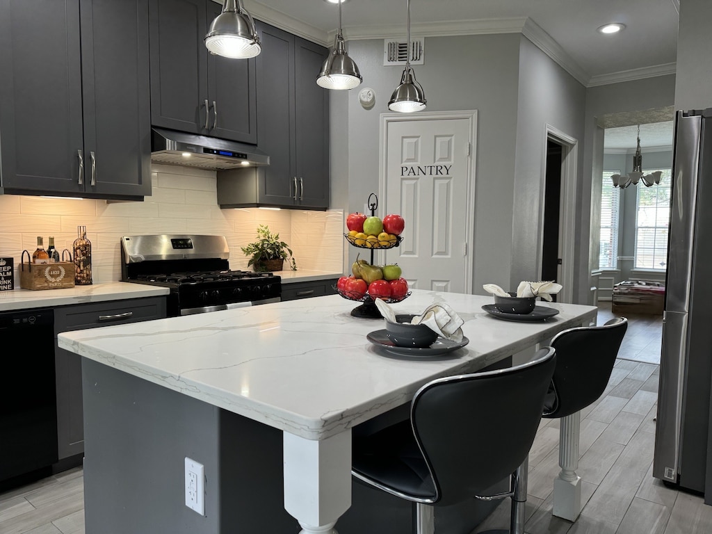 7923 Harvester St, Houston, TX 77095 - kitchen featuring appliances with stainless steel finishes, under cabinet range hood, crown molding, light stone counters, and decorative backsplash